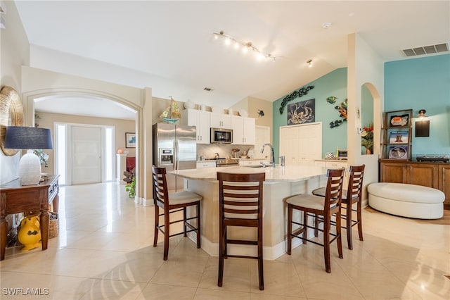 kitchen featuring sink, appliances with stainless steel finishes, a center island with sink, a kitchen bar, and decorative backsplash