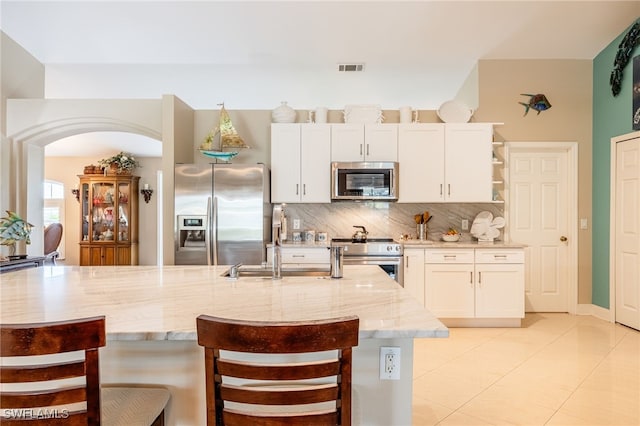 kitchen featuring light stone counters, white cabinetry, and stainless steel appliances