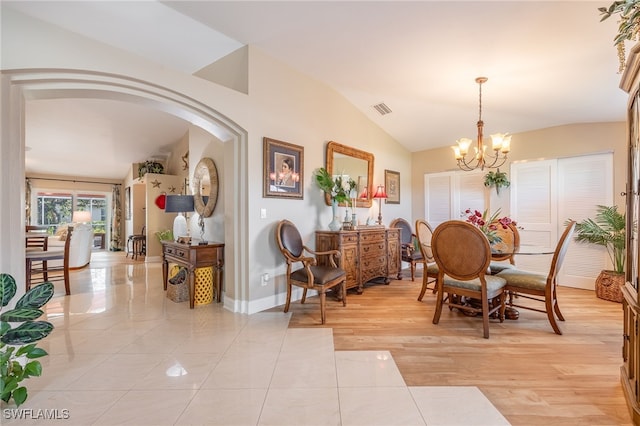 dining area featuring lofted ceiling, light hardwood / wood-style floors, and a notable chandelier