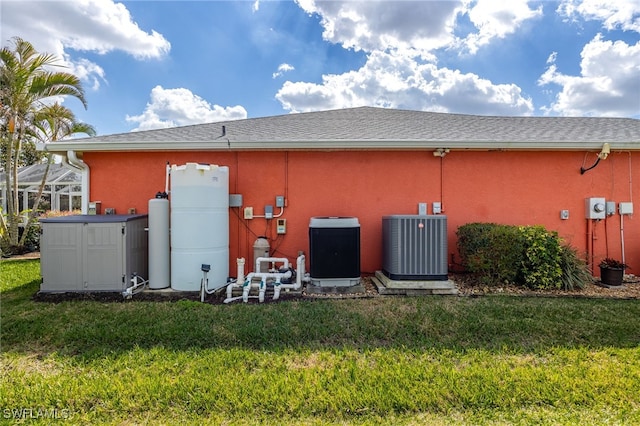 back of house with central air condition unit and a lawn