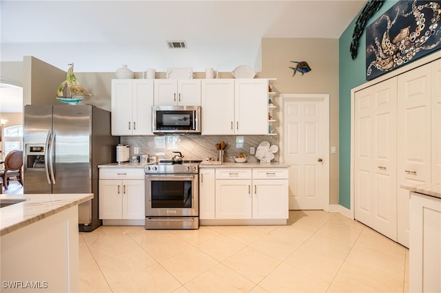 kitchen with stainless steel appliances, light stone countertops, decorative backsplash, and white cabinets