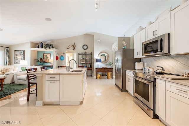 kitchen with white cabinetry, sink, vaulted ceiling, and appliances with stainless steel finishes