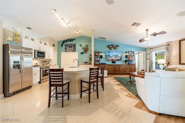 kitchen featuring sink, a breakfast bar, a kitchen island with sink, stainless steel appliances, and white cabinets