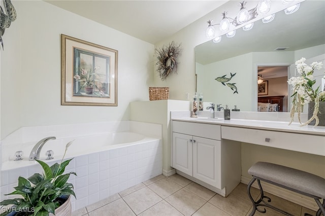 bathroom featuring tiled tub, vanity, and tile patterned flooring