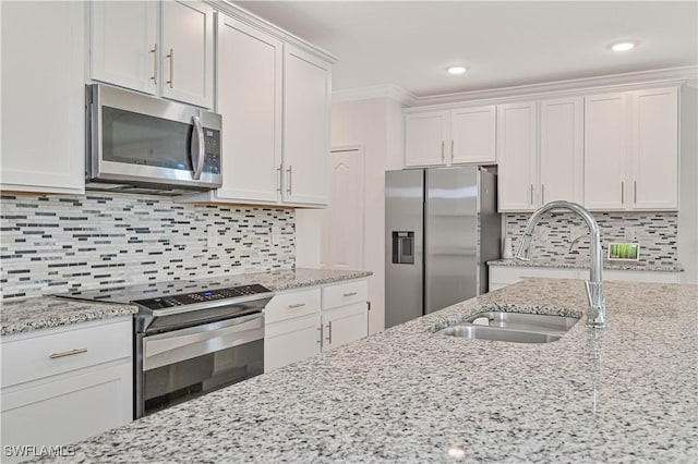 kitchen with stainless steel appliances, light stone countertops, sink, and white cabinets