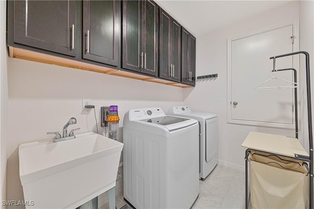 clothes washing area featuring light tile patterned flooring, cabinets, sink, and washer and dryer