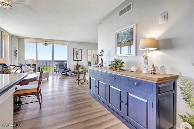 interior space featuring butcher block countertops, a wall of windows, blue cabinetry, and light wood-type flooring