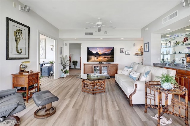 living room featuring ceiling fan, light hardwood / wood-style flooring, and indoor wet bar