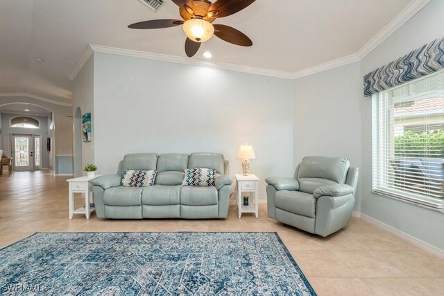 living area featuring a healthy amount of sunlight, baseboards, arched walkways, and ornamental molding