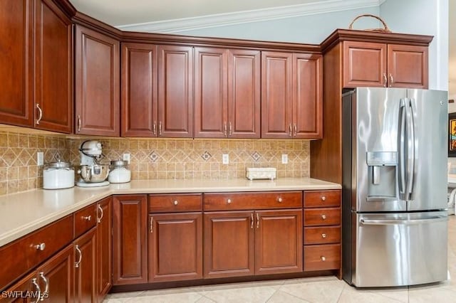 kitchen featuring light tile patterned floors, light countertops, decorative backsplash, ornamental molding, and stainless steel fridge with ice dispenser