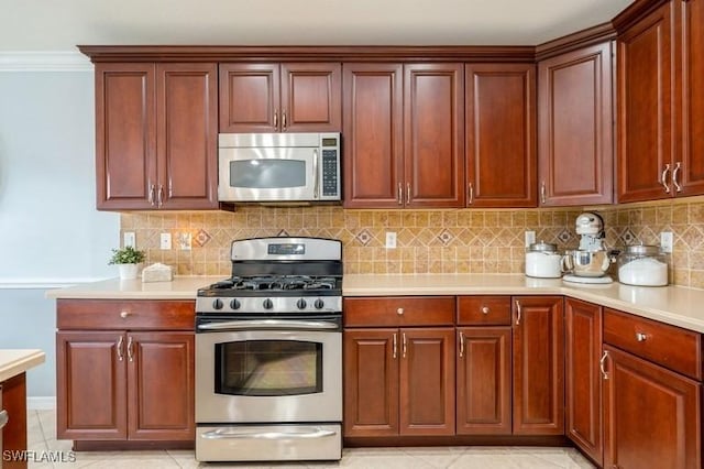 kitchen with appliances with stainless steel finishes, light countertops, backsplash, and ornamental molding