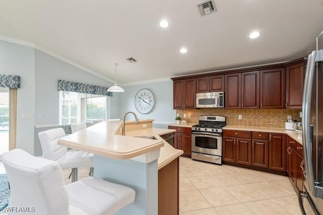 kitchen with a breakfast bar area, stainless steel appliances, light countertops, hanging light fixtures, and visible vents