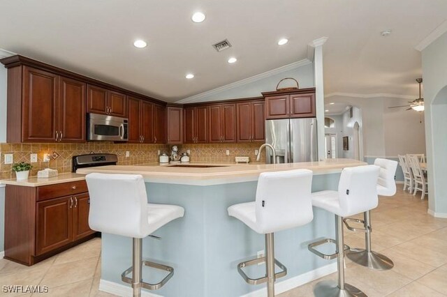 kitchen featuring light countertops, appliances with stainless steel finishes, a breakfast bar, and a kitchen island with sink