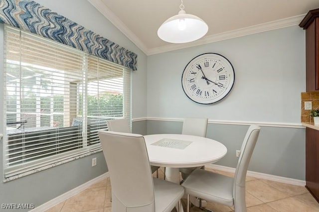 dining room with lofted ceiling, light tile patterned flooring, crown molding, and baseboards