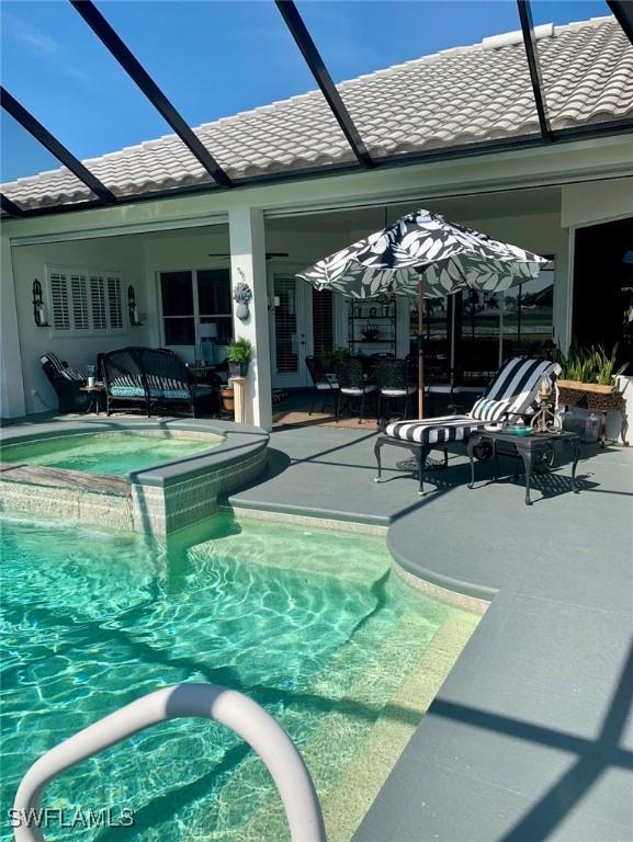 view of pool featuring a patio, an in ground hot tub, and a lanai