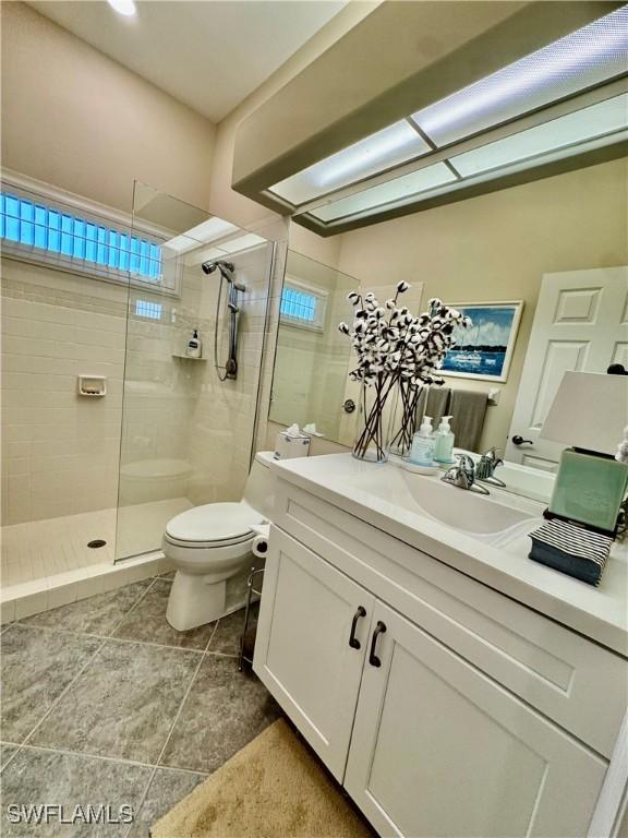 bathroom featuring vanity, tiled shower, and toilet