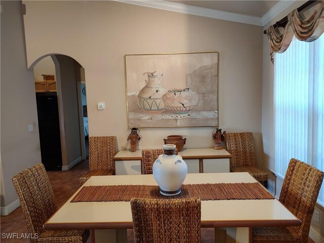 dining area with arched walkways, tile patterned flooring, and crown molding