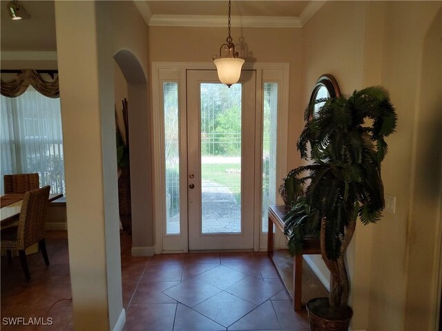 tiled entrance foyer featuring arched walkways and crown molding