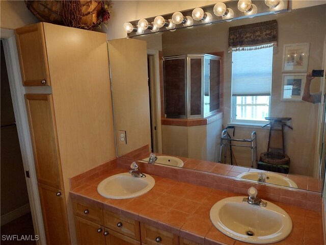 full bath with double vanity, a stall shower, and a sink