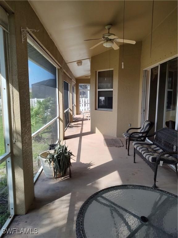 sunroom / solarium with lofted ceiling, ceiling fan, and a wealth of natural light