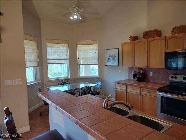 kitchen featuring decorative backsplash, tile countertops, stainless steel electric range, black microwave, and a sink