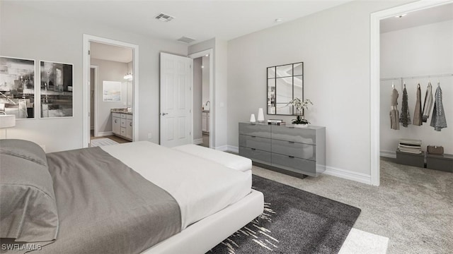 carpeted bedroom featuring ensuite bathroom, visible vents, and baseboards