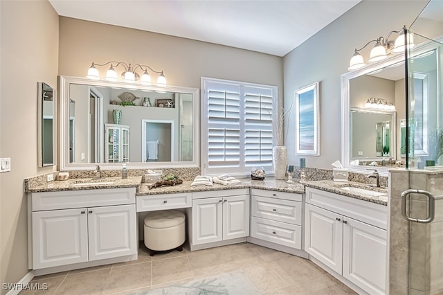 bathroom with a shower with door, vanity, and tile patterned flooring