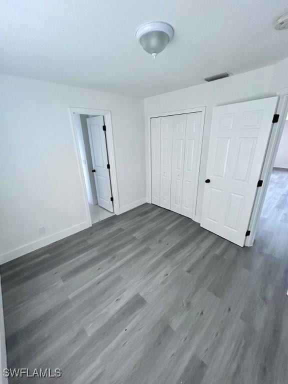 unfurnished bedroom featuring dark hardwood / wood-style floors and a closet