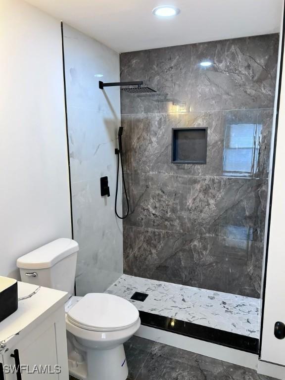 bathroom featuring tiled shower, vanity, and toilet