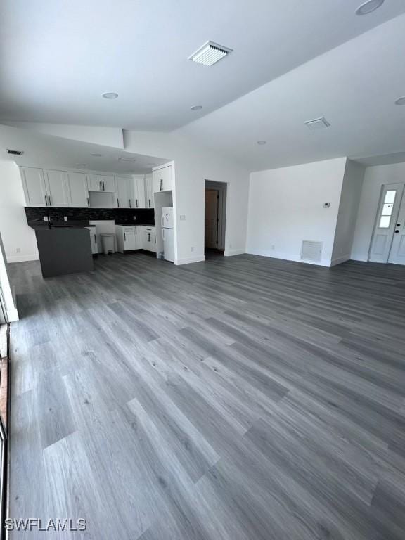 unfurnished living room with dark hardwood / wood-style floors and vaulted ceiling