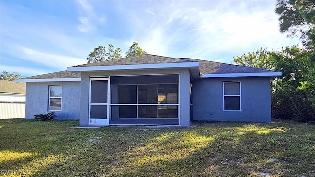 rear view of property featuring a lawn and a sunroom