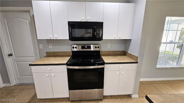 kitchen with white cabinetry, light tile patterned floors, and stainless steel range with electric stovetop