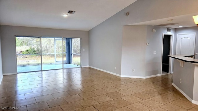 spare room featuring light tile patterned floors and vaulted ceiling