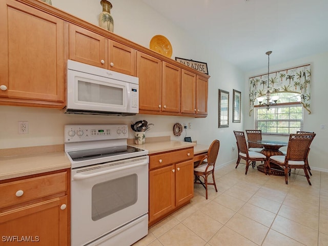 kitchen with light tile patterned flooring, white appliances, and decorative light fixtures