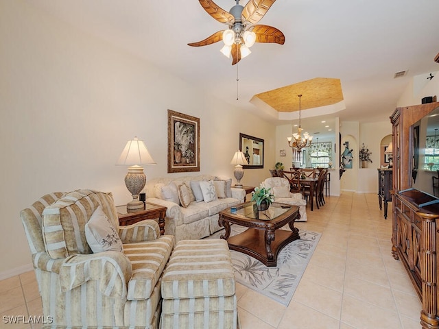 tiled living room with a raised ceiling and ceiling fan with notable chandelier