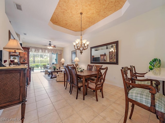 dining area featuring a raised ceiling, ceiling fan with notable chandelier, and light tile patterned floors