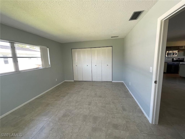 unfurnished bedroom with a closet, visible vents, a textured ceiling, and baseboards