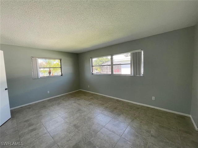 spare room featuring baseboards and a textured ceiling