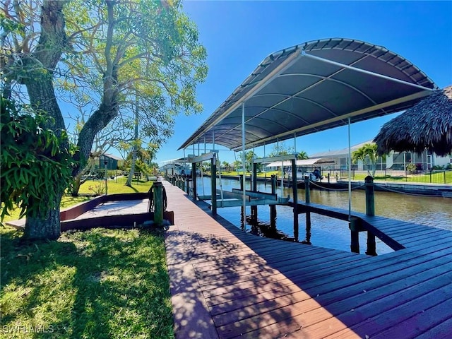 dock area featuring a lawn, a water view, boat lift, and a residential view