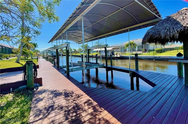 view of dock with a water view, fence, and boat lift