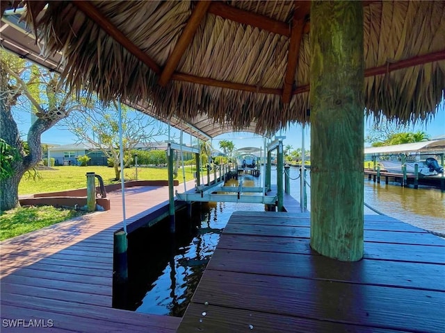 view of dock featuring a lawn, a water view, and boat lift