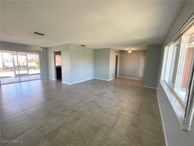 unfurnished living room featuring visible vents, a textured ceiling, and baseboards