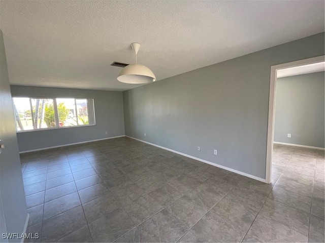 unfurnished room featuring a textured ceiling and baseboards