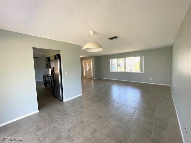 tiled empty room with visible vents, a textured ceiling, and baseboards