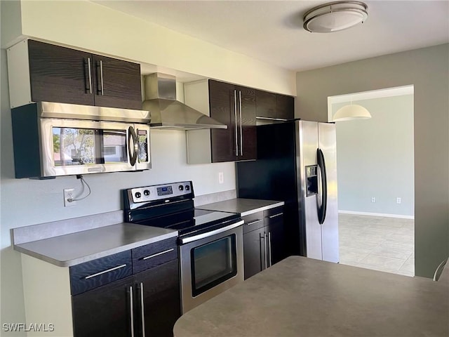 kitchen featuring baseboards, wall chimney exhaust hood, and stainless steel appliances