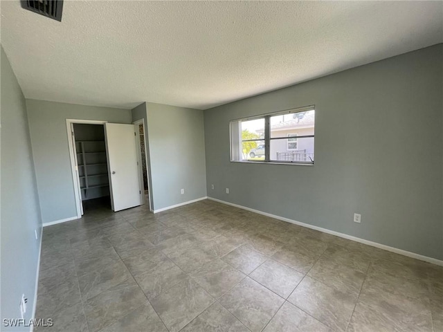 unfurnished bedroom with a textured ceiling, visible vents, and baseboards