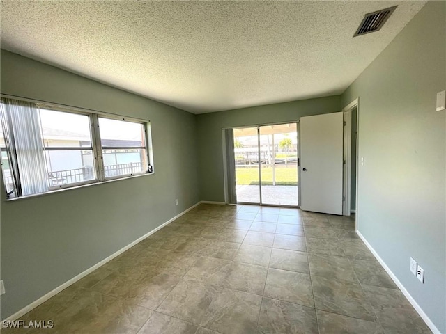 empty room with a textured ceiling, visible vents, and baseboards