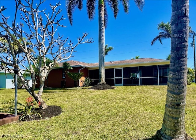 back of house featuring a sunroom and a lawn