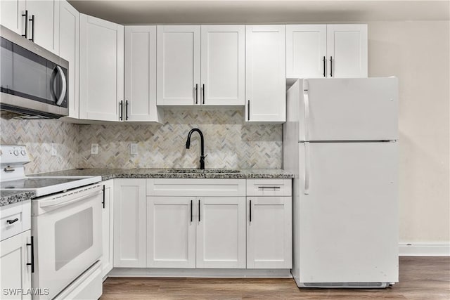 kitchen featuring white appliances, white cabinetry, sink, and stone counters