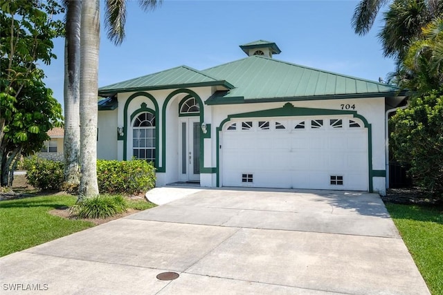 704 107th Ave N, Naples, FL 34108 - view of front of home with an attached garage, stucco siding, metal roof, and concrete driveway